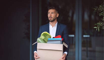 man carrying items in a box out of his office after he is fired