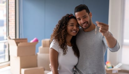 couple smiling and holding a key to their new house