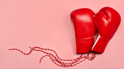 Red pair of boxing gloves on a pink background