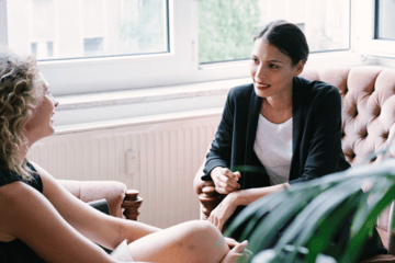 Young woman in an office sitting on a couch speaking to a Money Coach sitting across from her