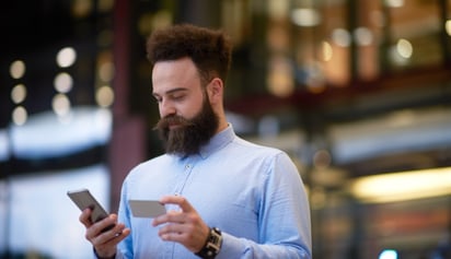 man holding his phone and his credit card