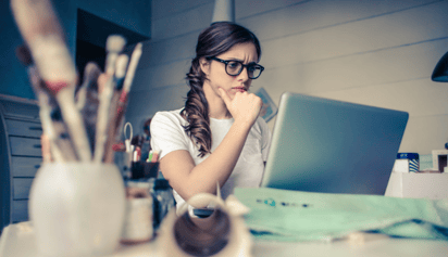 woman wearing glasses working on her laptop and thinking