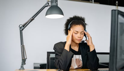 woman wearing headphones holding her head