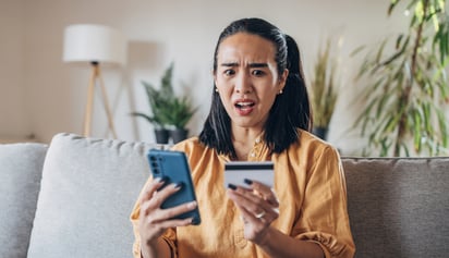 woman looking at her credit card after being scammed