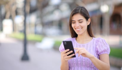 woman smiling and using her phone