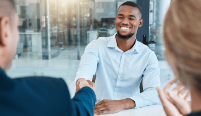 man in light blue shirt shaking hands during an interview