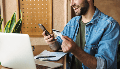 man looking at his phone and using his credit card
