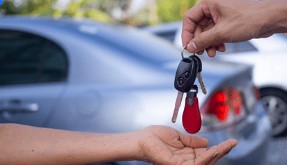 person handing over car keys to another person