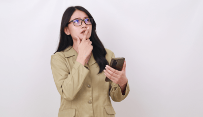 woman wearing glasses thinking and holding her phone