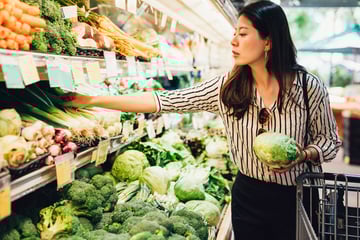 Young woman grocery shopping holding a head of lettuce